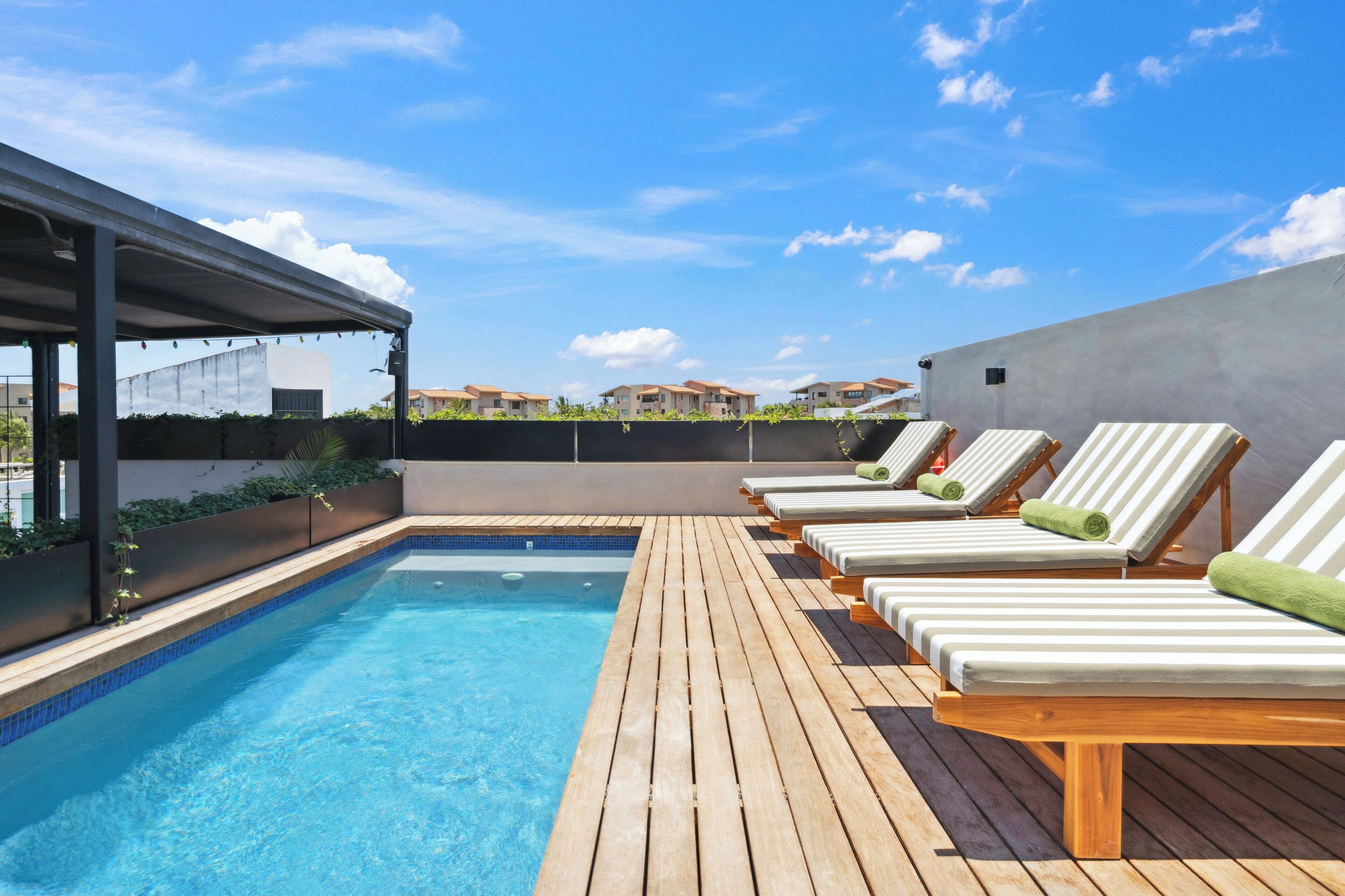 A rooftop pool area with lounge chairs and a covered seating area.