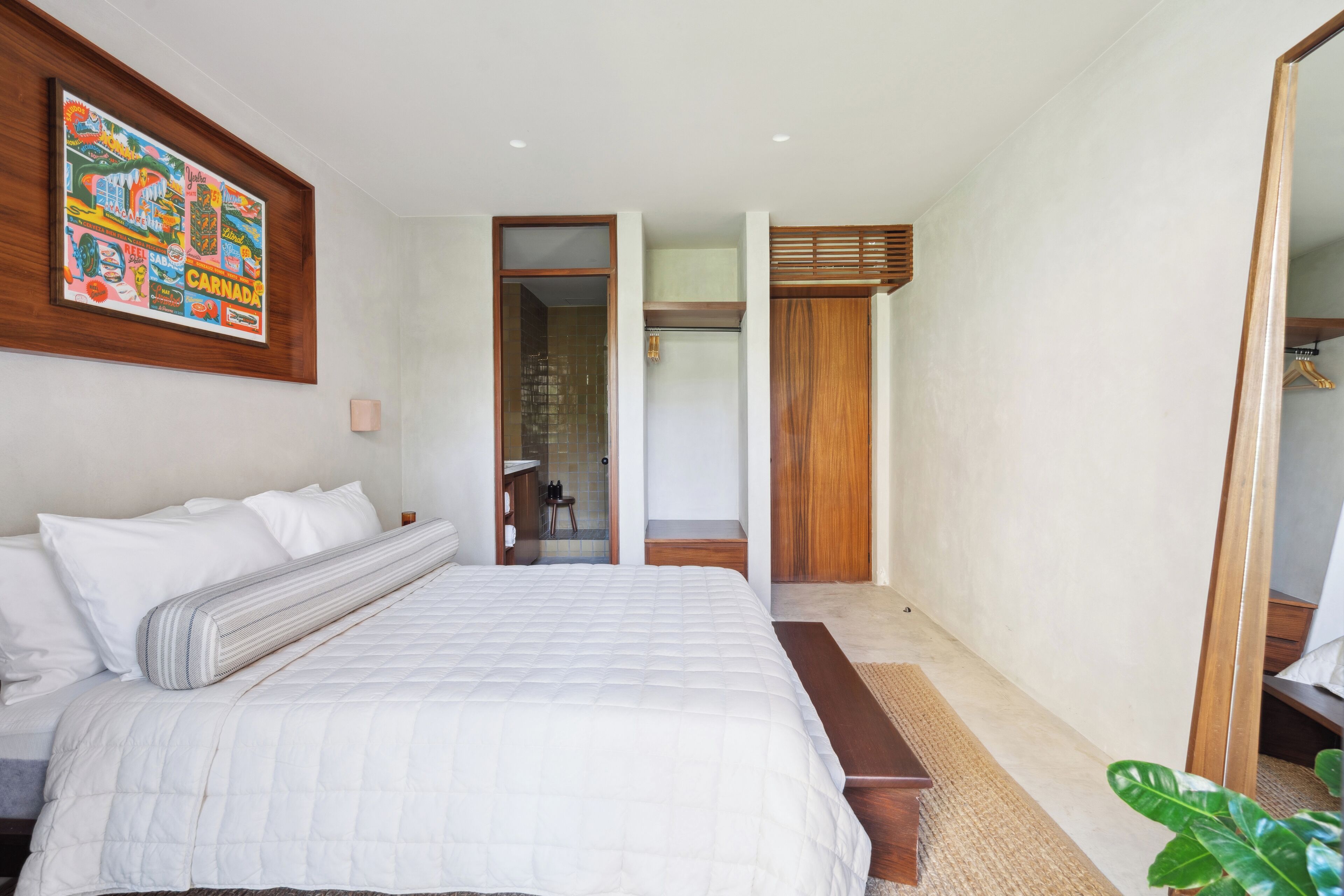 Un dormitorio con una cama grande, cabecera de madera, un espejo y una obra de arte colorida en la pared.