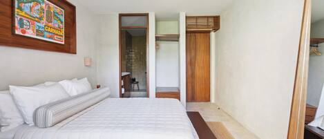 Un dormitorio con una cama grande, cabecera de madera, un espejo y una obra de arte colorida en la pared.