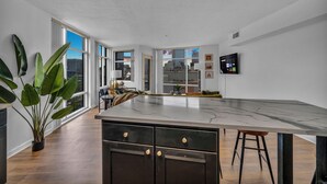 A modern kitchen with a large island, wooden flooring, and large windows offering city views. - City-view, Free Parking, 24/7 Gym (Cleveland)