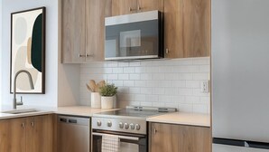 Een moderne keuken met houten kastjes, roestvrijstalen apparatuur en een betegelde spatwand.