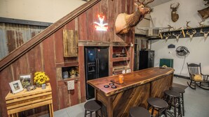 Un rústico espacio de bar con taburetes de madera, un letrero de neón y monturas de animales en la pared.