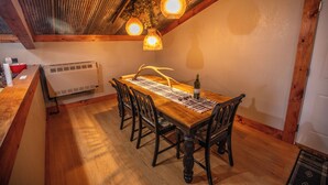 Un comedor con mesa de madera, sillas y lámparas colgantes.