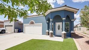 A residential house with a blue exterior, a white garage door, and a well-maintained lawn.