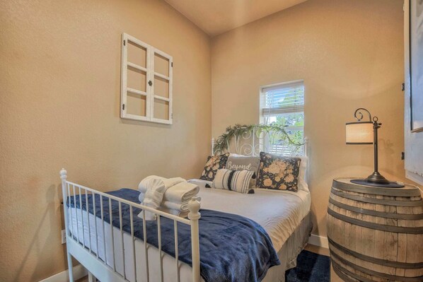 A bedroom with a bed, a window, a lamp, and a wooden barrel.