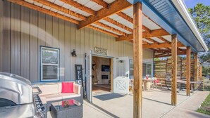 Un espace extérieur abrité avec des sièges, un barbecue, un panneau d’accueil et une enseigne indiquant « Quartier des cow-boys ».