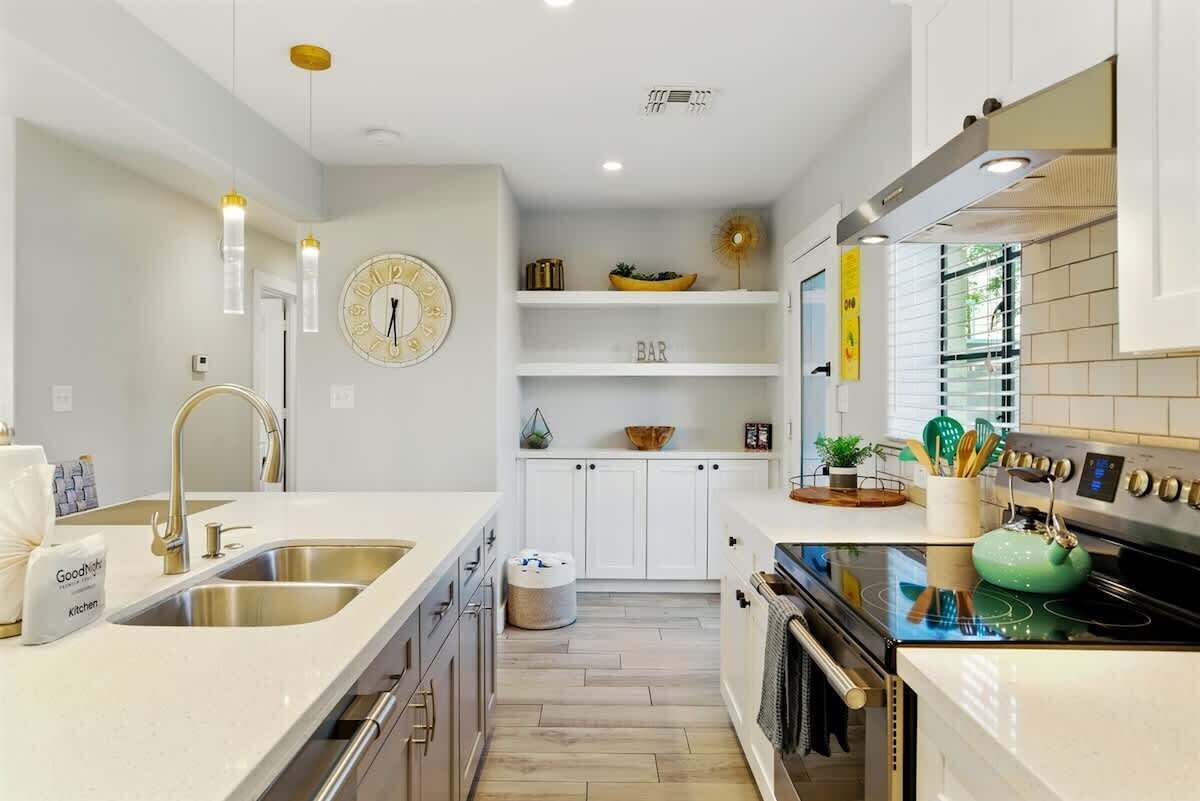 A modern kitchen with white cabinetry, stainless steel appliances, and a central island.