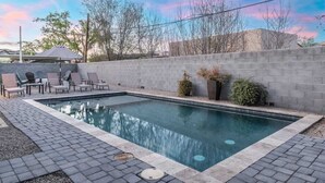 A rectangular swimming pool with a tiled deck, surrounded by a low brick wall and a row of lounge chairs. - Walk 2 Old Town, Sparkling Pool, Fire Pit, Oasis (Scottsdale)