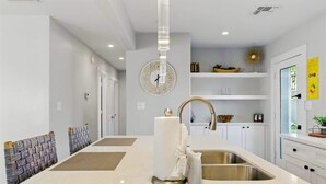 A modern kitchen with a central island, white cabinetry, and a large wall clock. - Walk 2 Old Town, Sparkling Pool, Fire Pit, Oasis (Scottsdale)