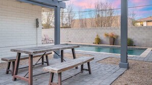 A covered patio with a pool, wooden table and benches, and a brick wall. - Walk 2 Old Town, Sparkling Pool, Fire Pit, Oasis (Scottsdale)