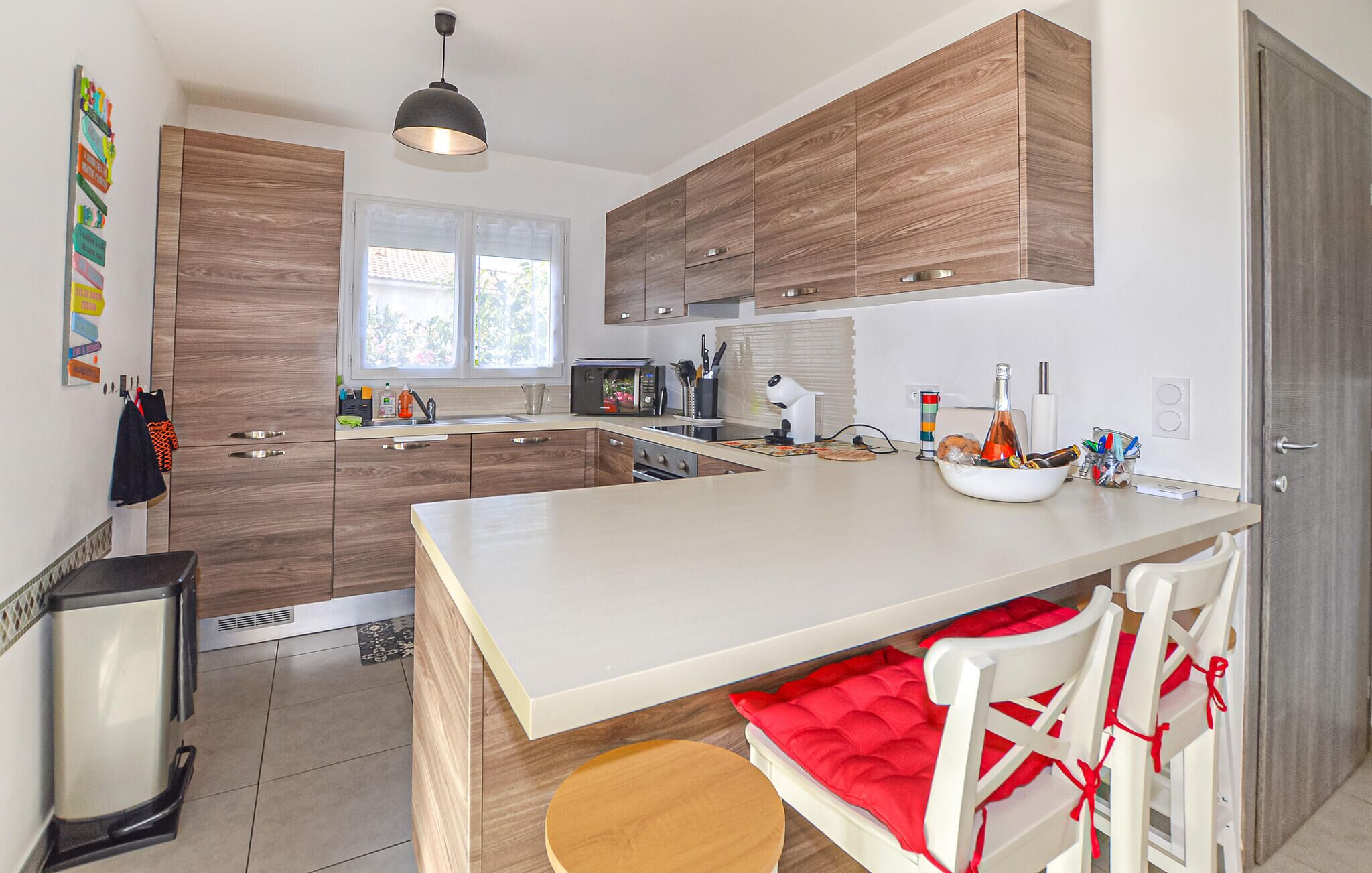 Una cucina moderna con mobili in legno, un'isola grande e un'area pranzo con sedie bianche.