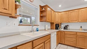 A kitchen with wooden cabinets, a dishwasher, and a window with blinds. - Spacious 4-BR Home, Near Fool Hollow Lake (Show Low)