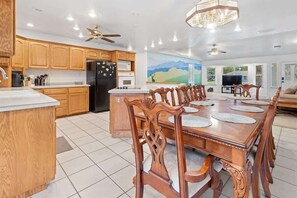 Una cocina amplia con armarios de madera, una isla central y un comedor con una gran mesa y sillas de madera.