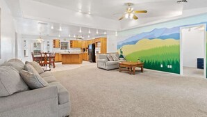 A spacious living room with a sofa, a coffee table, and a painting of a landscape. - Spacious 4-BR Home, Near Fool Hollow Lake (Show Low)