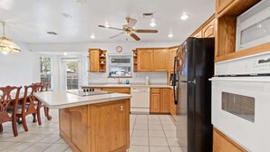 A kitchen with wooden cabinets, a black refrigerator, a white stove, and a ceiling fan. - Spacious 4-BR Home, Near Fool Hollow Lake (Show Low)
