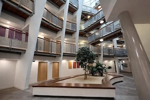 Een meerlaags atrium met een centrale plantenbak, houten vloer en modern ontwerp.