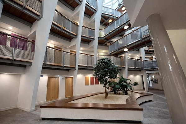 A multi-level atrium with a central planter, wooden flooring, and a modern design.
