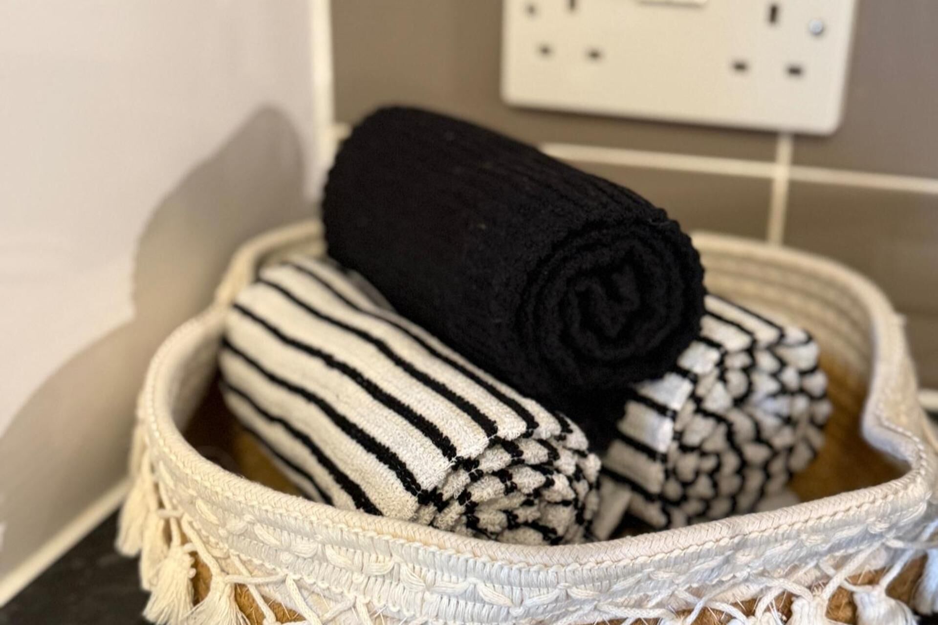 Un panier contenant des serviettes enroulées à rayures noires et blanches.