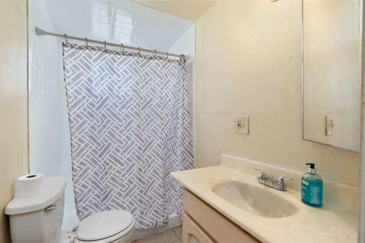 A bathroom with a toilet, a sink, a mirror, and a shower curtain.