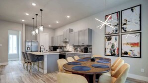 A modern kitchen with a central island, pendant lighting, and abstract art on the wall.