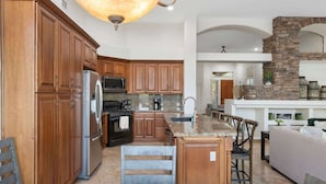 A spacious kitchen with wooden cabinets, a granite countertop, and a central island. - Lakeside home with private patio, Grill, Golf view (Glendale)