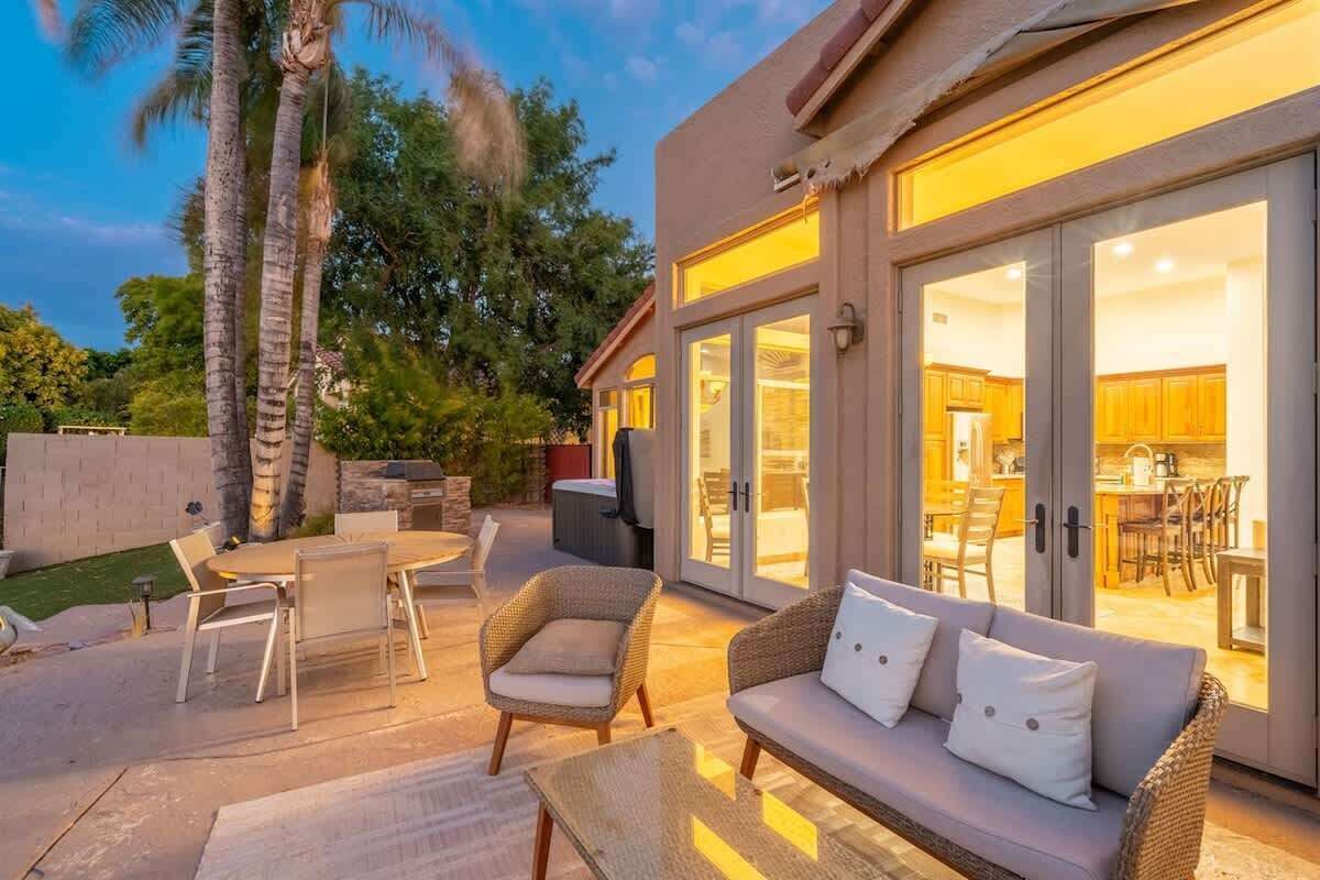 An outdoor patio with a dining table, chairs, a sofa, and a grill.