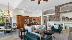 A spacious living area with a ceiling fan, a dining area with a chandelier, and a kitchen with stone accents. - Lakeside home with private patio, Grill, Golf view (Glendale)