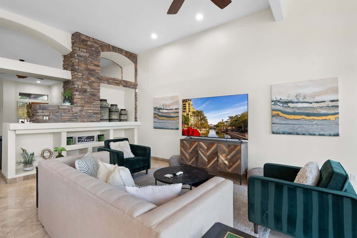 A modern living room with a stone fireplace, a sofa, a coffee table, and artwork on the walls.
