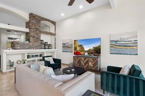 A modern living room with a stone fireplace, a sofa, a coffee table, and artwork on the walls.
