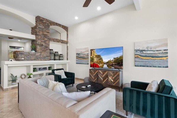A modern living room with a stone fireplace, a sofa, a coffee table, and artwork on the walls. - Lakeside home with private patio, Grill, Golf view (Glendale)
