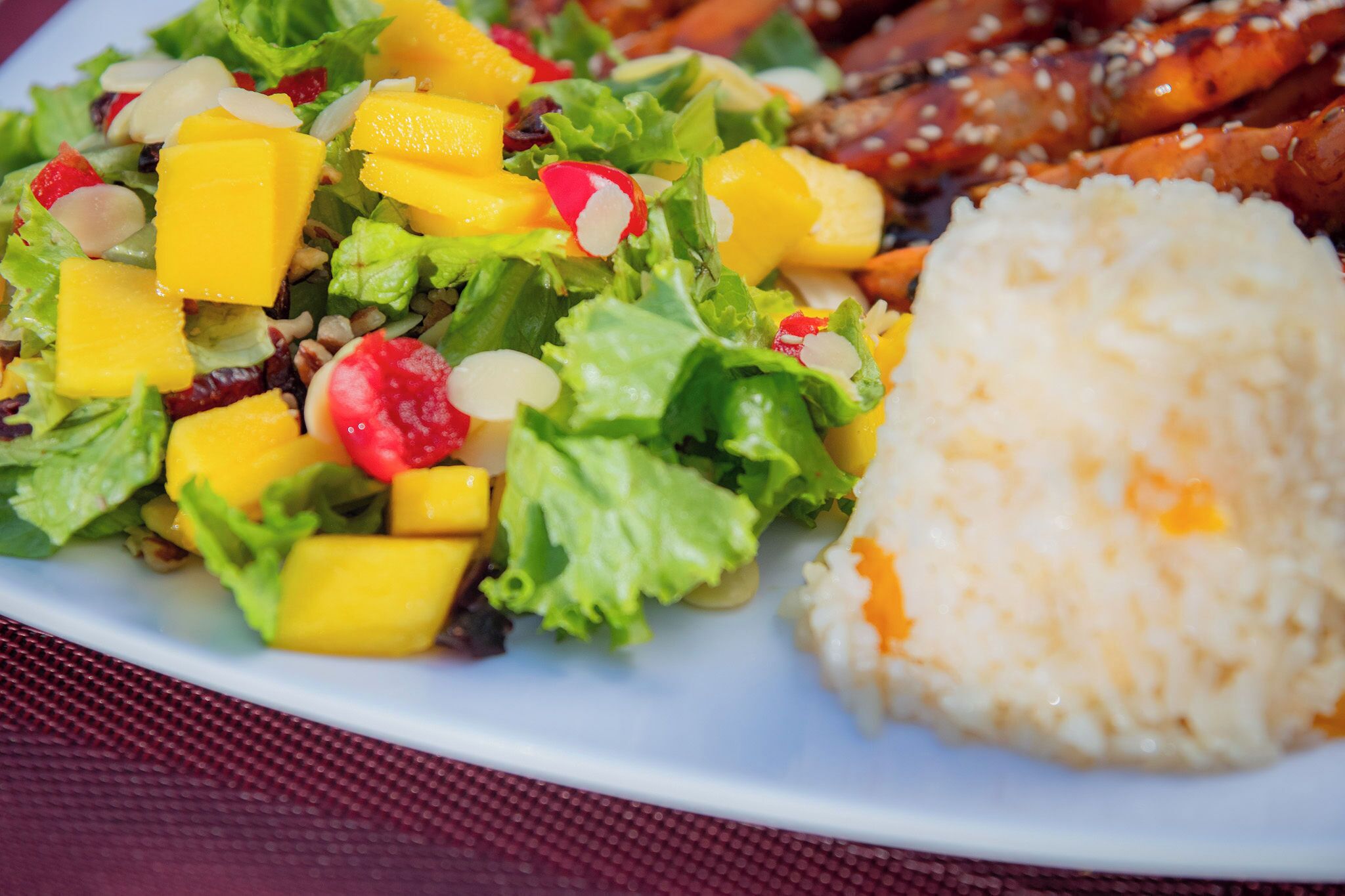 A plate with a salad, rice, and grilled chicken wings.