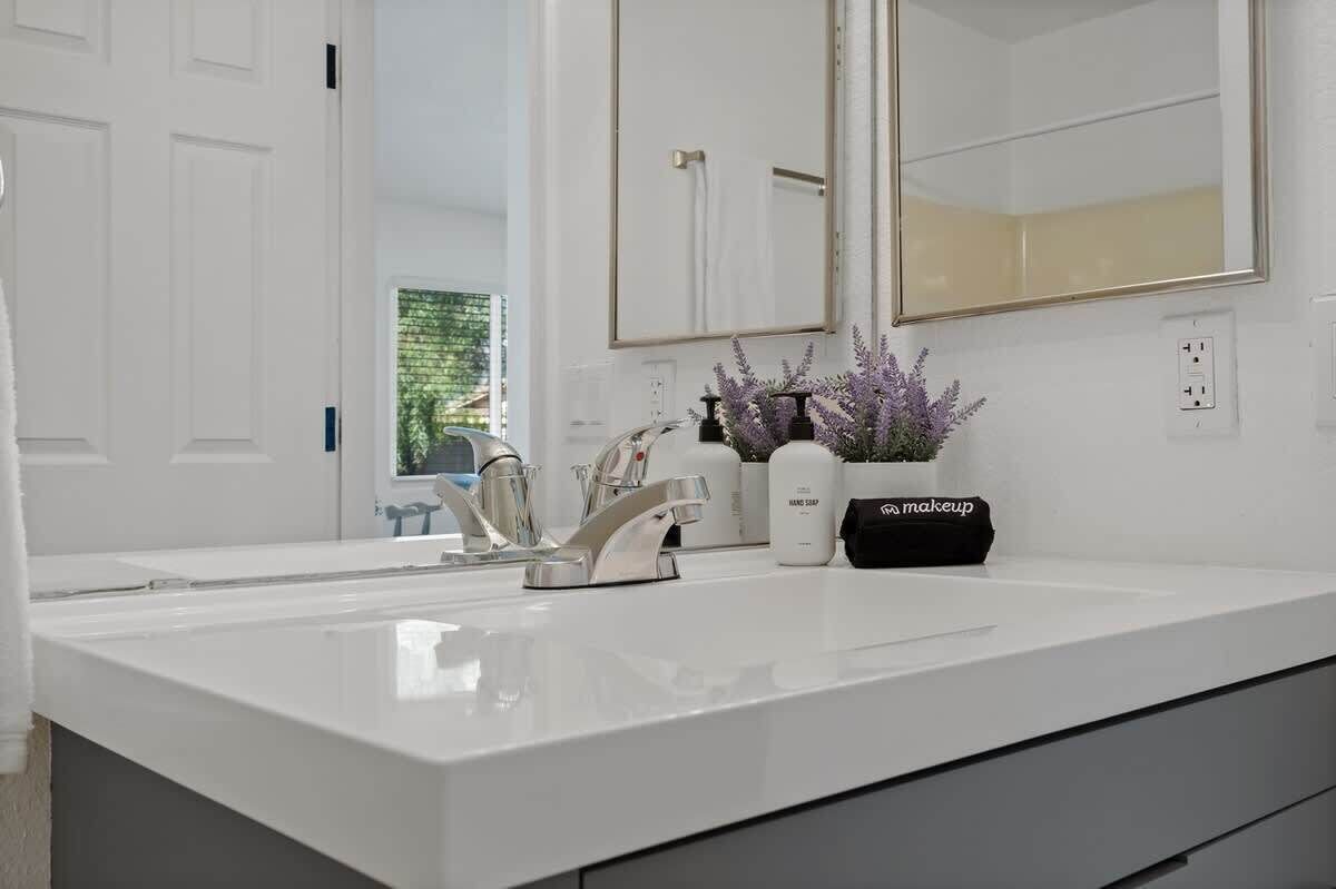 Une salle de bain moderne avec un lavabo blanc, un miroir et une plante en pot.