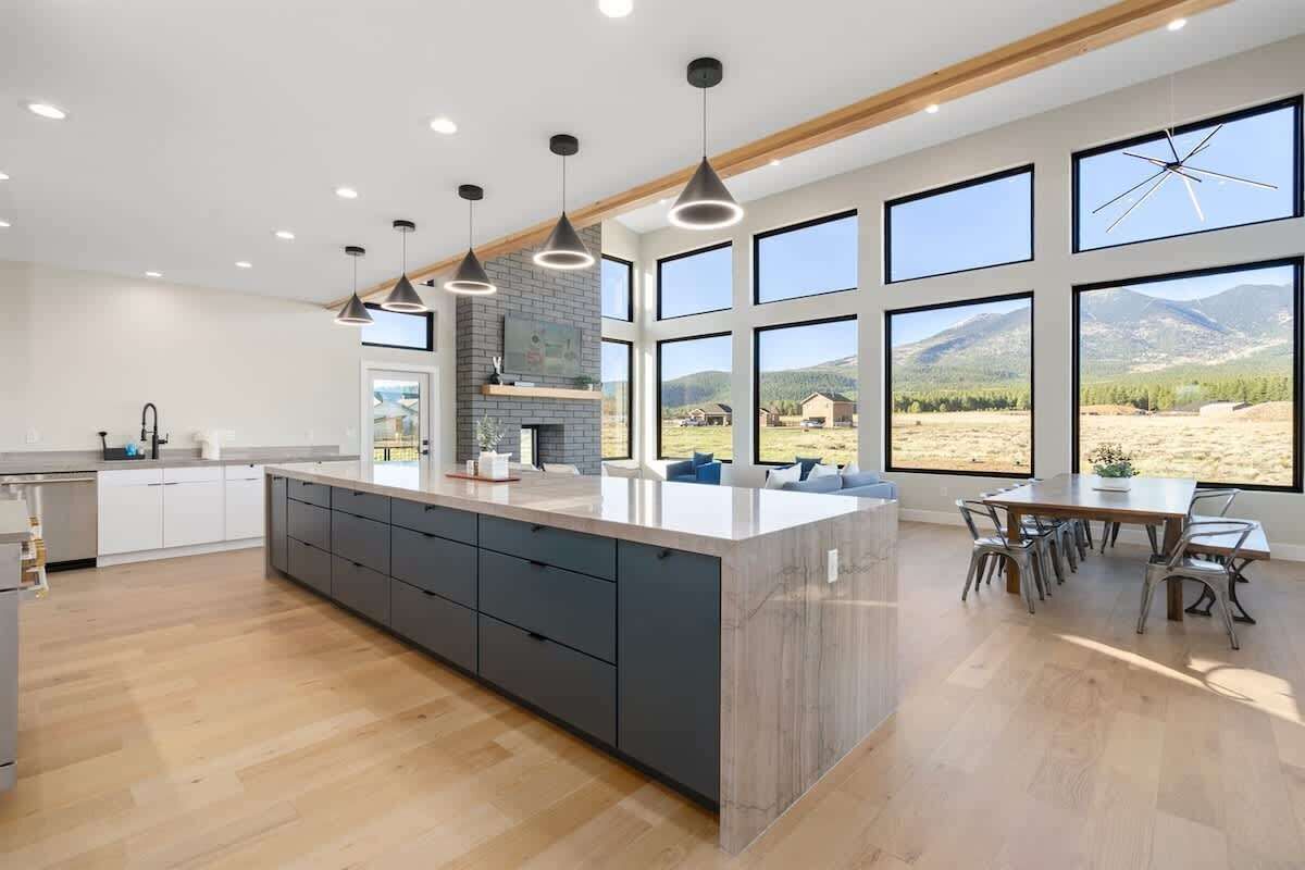 A modern kitchen with a large island, dark cabinetry, and pendant lighting.