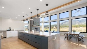 A modern kitchen with a large island, dark cabinetry, and pendant lighting. - The Bluebird Flagstaff, Jacuzzi, Sleeps 26 (Flagstaff)