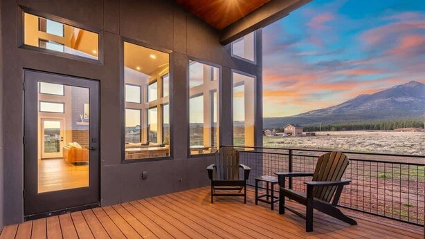 A deck with wooden flooring, two Adirondack chairs, and a view of a mountain and river. - The Bluebird Flagstaff, Jacuzzi, Sleeps 26 (Flagstaff)
