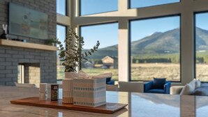 A modern living room with a large window overlooking a mountainous landscape. - The Bluebird Flagstaff, Jacuzzi, Sleeps 26 (Flagstaff)