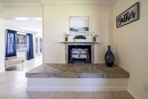 A spacious living room with a fireplace, a bench, and a large vase.