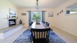 A dining area with a long table, chairs, a fireplace, and a view through large windows. - Beautiful 2bd with River Views & Amazing Sunsets (Fort Myers)