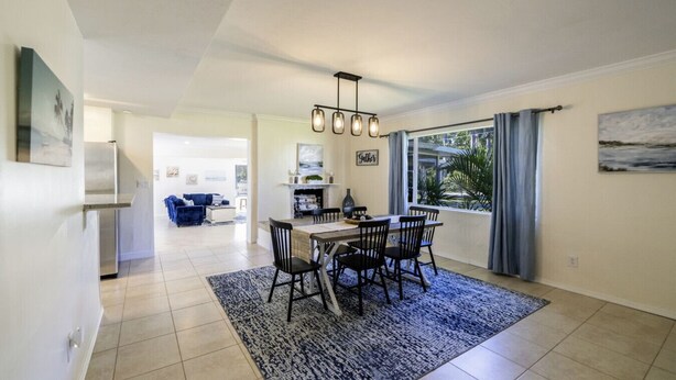 A modern kitchen with a dining area, featuring a central island, a chandelier, and a view of the outdoors. - Beautiful 2bd with River Views & Amazing Sunsets (Fort Myers)
