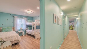 A bedroom with bunk beds, a bedside table, a lamp, and a window with curtains. - Pineapple Pad:ACROSS from beach + boardwalk + parking w/ Full Linen Service! (Ocean City)
