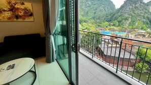 Une pièce dotée d’une porte vitrée donnant sur un balcon avec vue sur un paysage montagneux et une piscine.