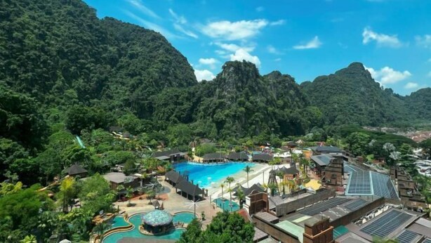 Un complexe hôtelier doté d’une grande piscine, entourée d’une végétation luxuriante et de montagnes.