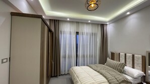Une chambre à coucher moderne avec un grand lit, une table de chevet, une commode et un luminaire au plafond.