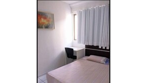 Ein Schlafzimmer mit einem Bett, einem Schreibtisch und einem Sessel.