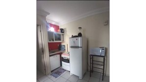 Eine kleine Küche mit Kühlschrank, Mikrowelle und einem Tisch.