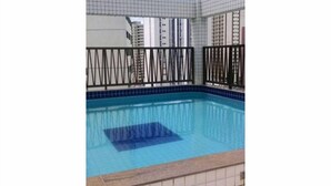 Ein Schwimmbecken mit gefliestem Sonnendeck und einem schwarzen Metallzaun.