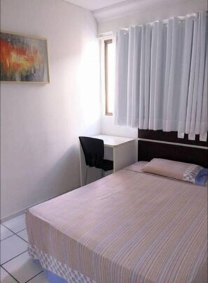 A bedroom with a bed, a desk, and a chair.