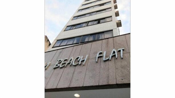 Ein hohes Gebäude mit dem Schriftzug "BEACH FLAT" auf der Fassade.
