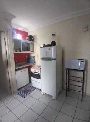 A compact kitchen with a refrigerator, microwave, and a small table.