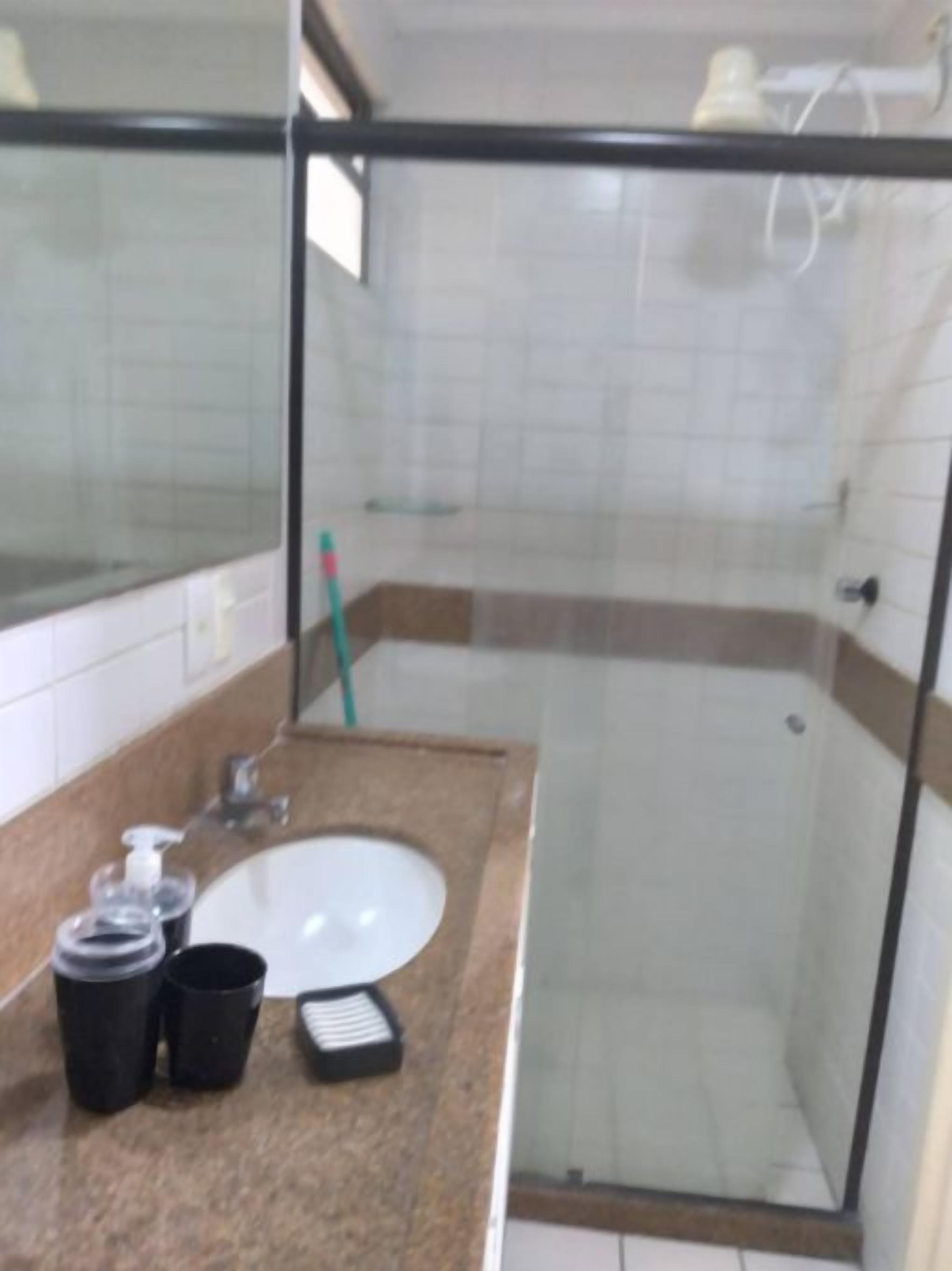 Un bagno con doccia vetrata, lavandino e specchio.
